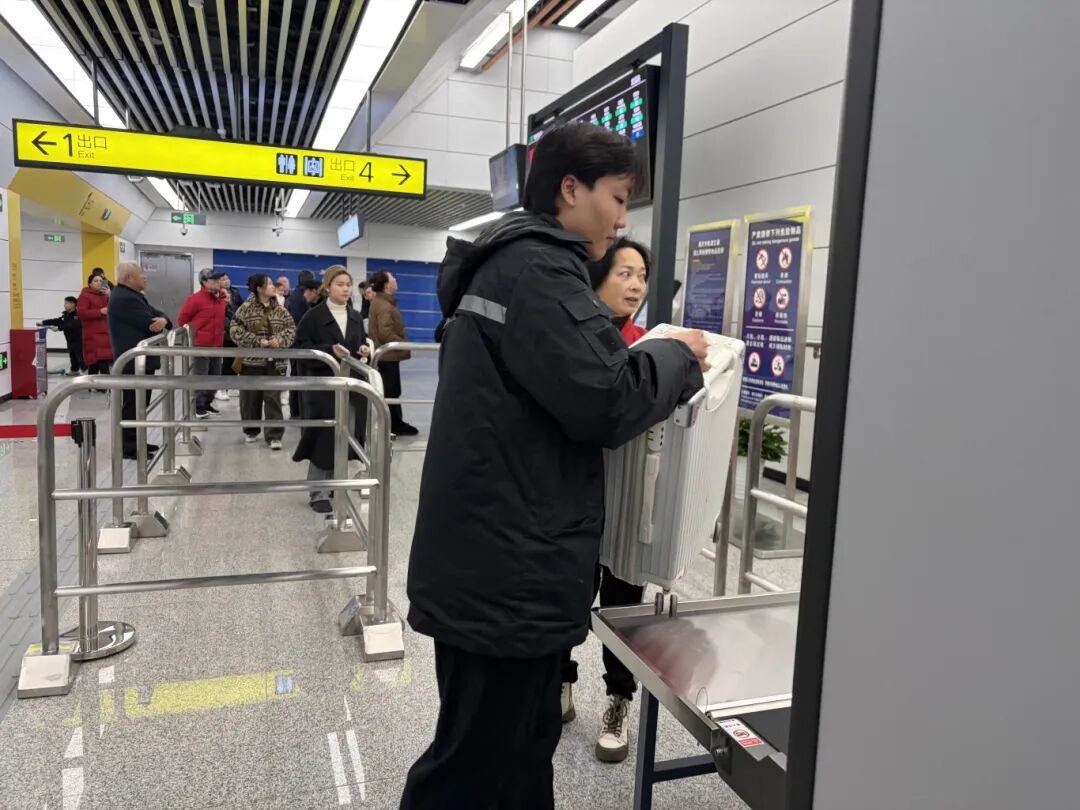 交通资源开发公司通邑公司4号线龙溪站安检员李旭炜帮助携带大件行李乘客过安检.jpg